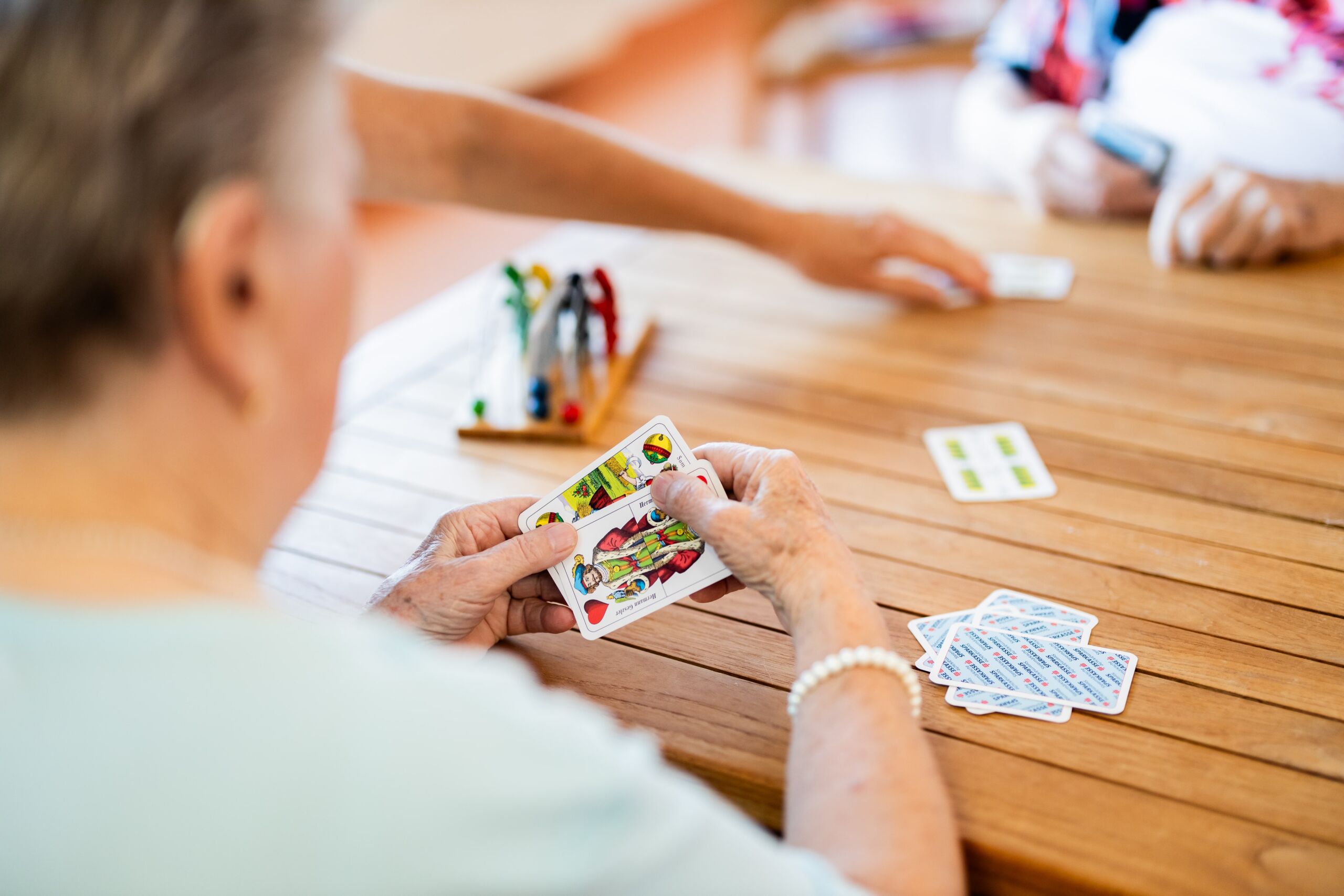 Seniorenhaus-Menda-Bewohner spielen gemeinsam Karten an einem Tisch, Nahaufnahme der Hände