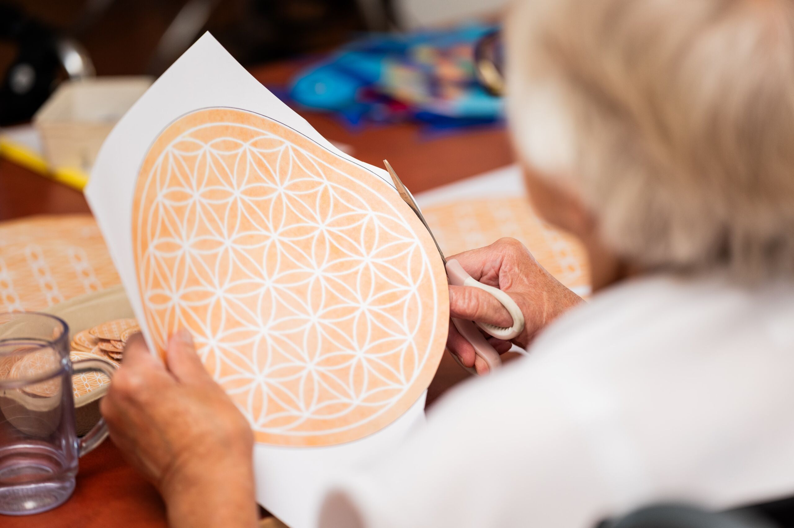 Bewohnerin des Augustinerhof hält ein rundes Mandala in den Händen um es auszuschneiden.